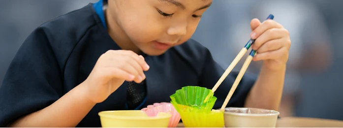おやつの皿とコップを前にする子どもの手元
