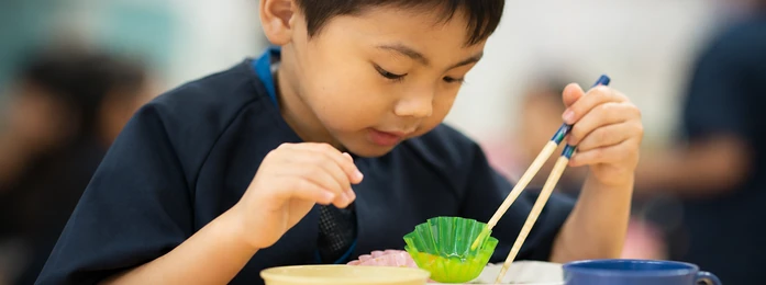 おやつの皿とコップを前にする子どもの手元