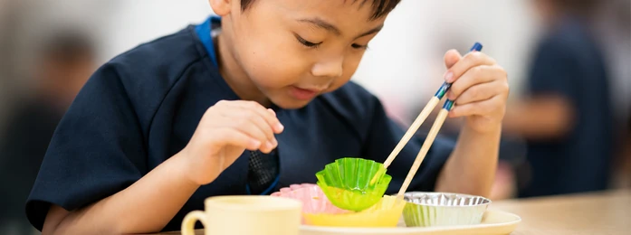 おやつの皿とコップを前にする子どもの手元