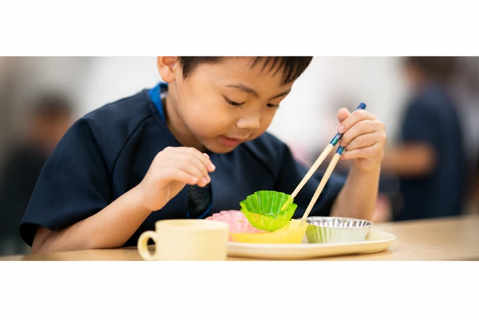 おやつの皿とコップを前にする子どもの手元
