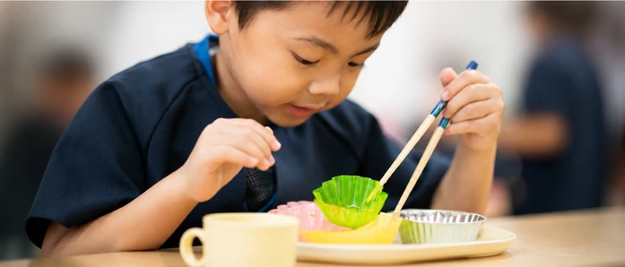 おやつの皿とコップを前にする子どもの手元