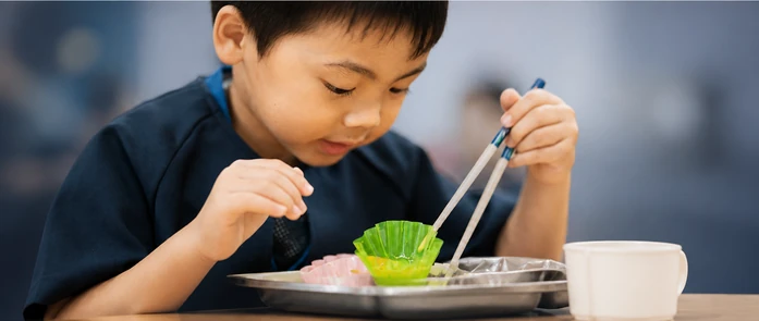 おやつの皿とコップを前にする子どもの手元