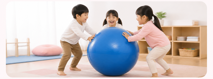 室内で子どもたちが青い大きなボールで遊ぶ様子