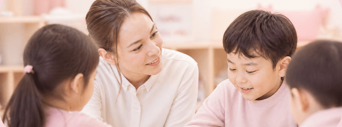 教室で女性が子どもたちに笑顔で話しかけている