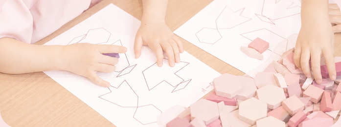 紙の図形に色付きブロックを置く子どもの手